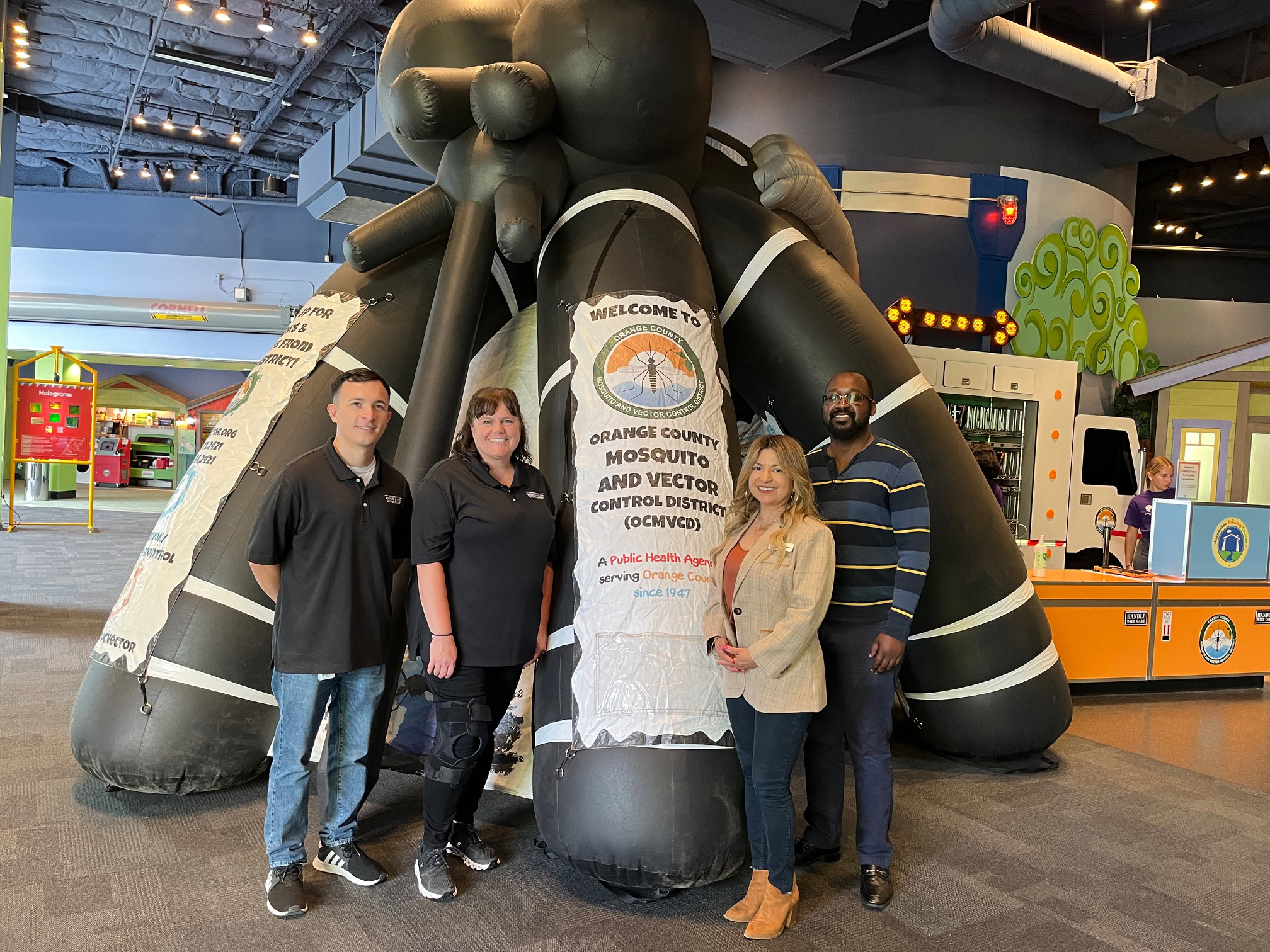 People taking a photo in front of a giant inflatable mosquito.
