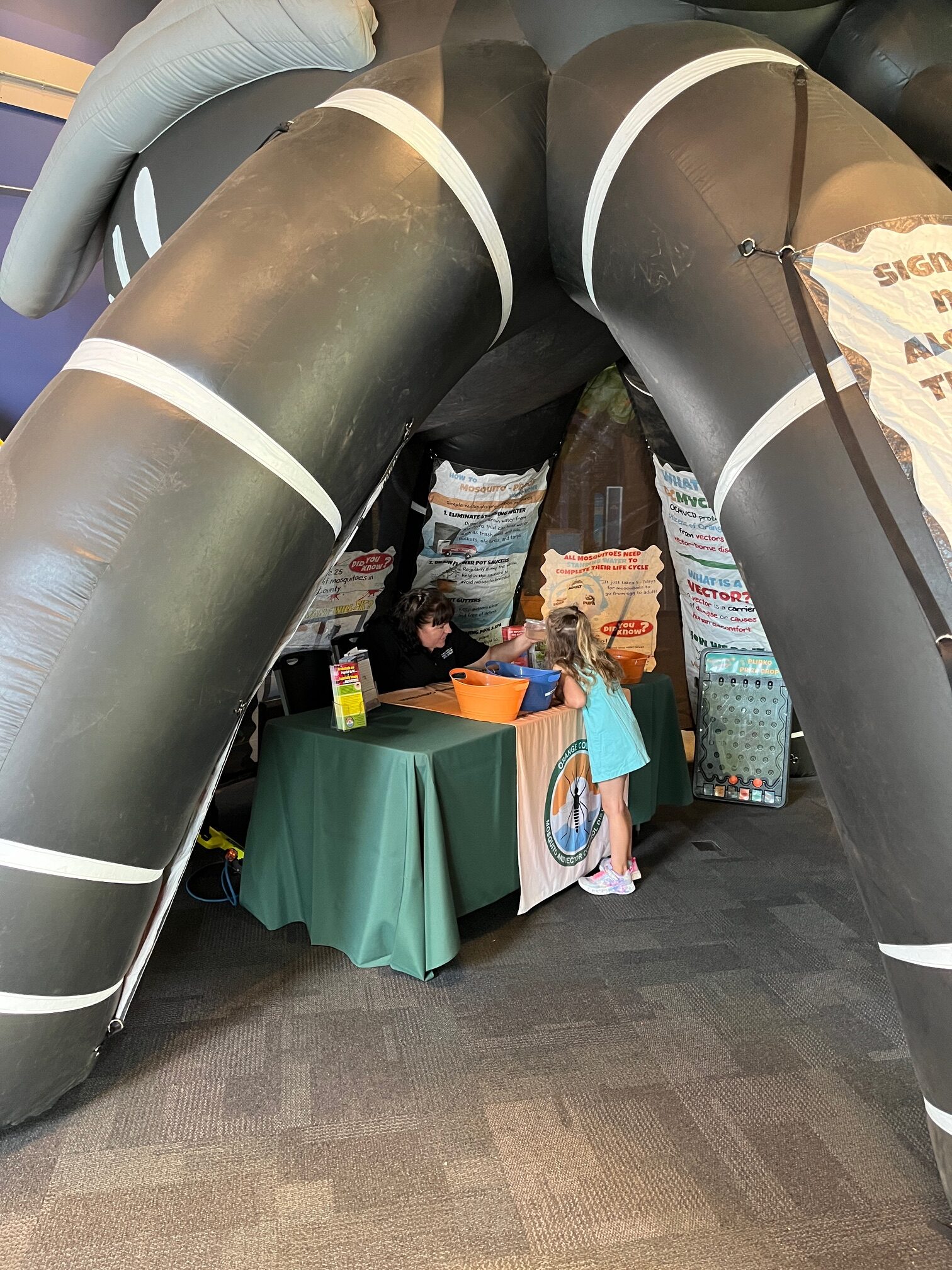 Giant inflatable mosquito with an information table inside.