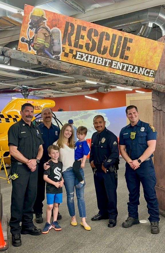 A family taking a photo with rescue services in front of an exhibit called Rescue Exhibit.