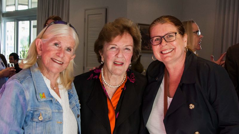 Three attendees smiling at an event.